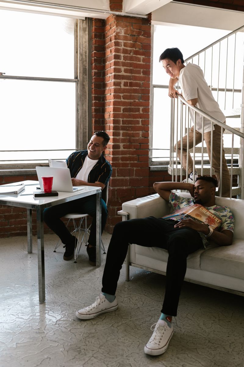 A group of friends sitting around a table with smartphones and receipts, dividing shared expenses.