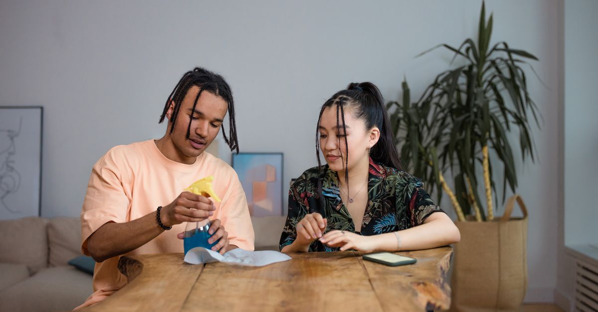 A group of friends sitting around a table with smartphones and receipts, dividing shared expenses.